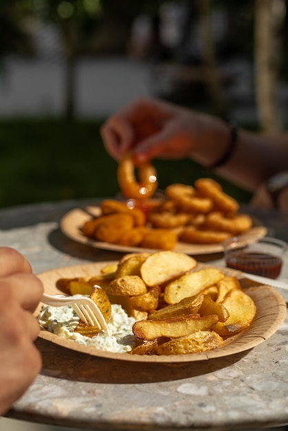 Fried potatoes and onion rings on a plate fast food street food