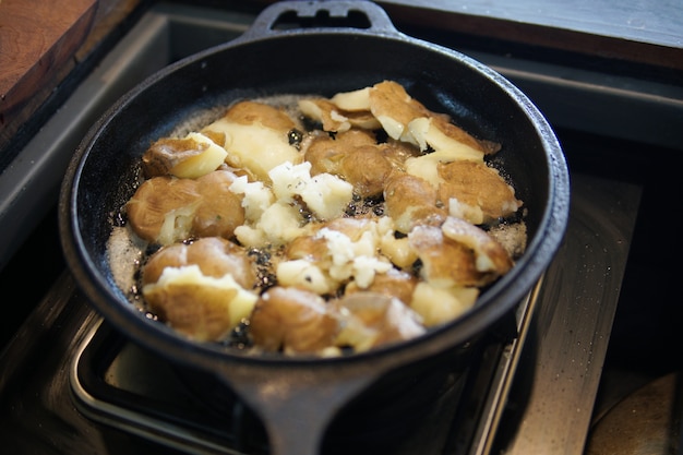 Fried potatoes roasting in frying pan in kitchen