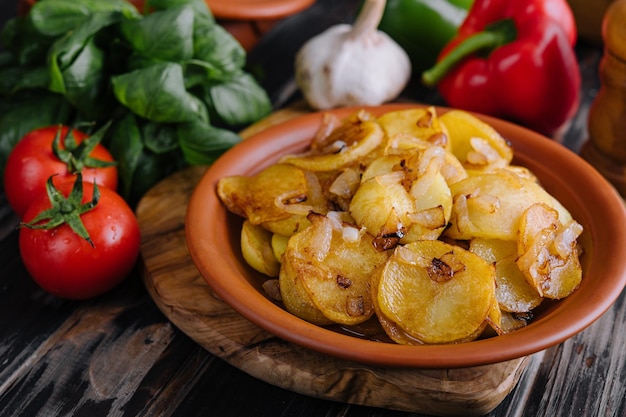 Fried potatoes with onions on wooden tray