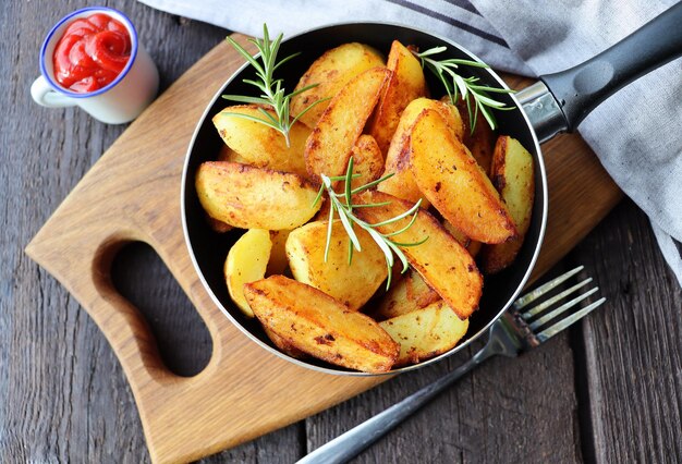 Photo fried potatoes with rosemary in iron pan