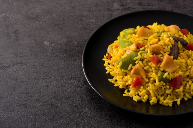 Fried rice with chicken and vegetables on black plate