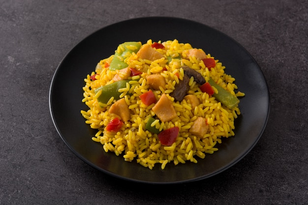 Fried rice with chicken and vegetables on black plate