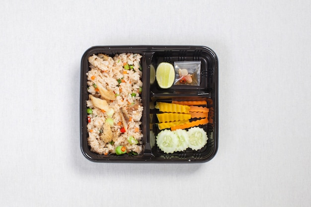 Fried rice with fried fish put in black plastic box, put on a white tablecloth, food box, Thai food.