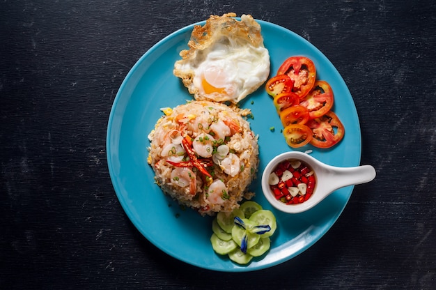 Fried rice with shrimp and fried egg on black wooden table, Thai food.