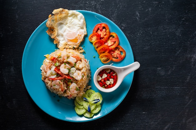 Fried rice with shrimp and fried egg on black wooden table, Thai food.