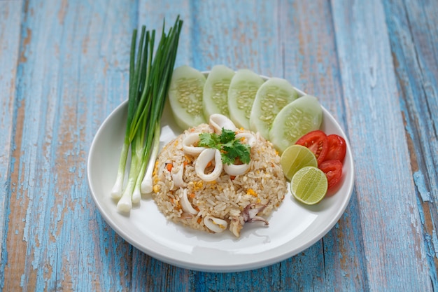 Fried rice with squid served with spring onion, cucumber, coriander, tomato and lime