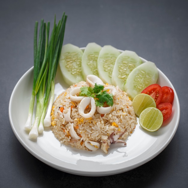 Fried rice with squid served with spring onion, cucumber, coriander, tomato and lime