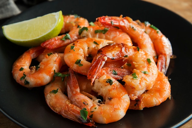 Fried roasted shrimps in plate with lemon greens parsley garlic