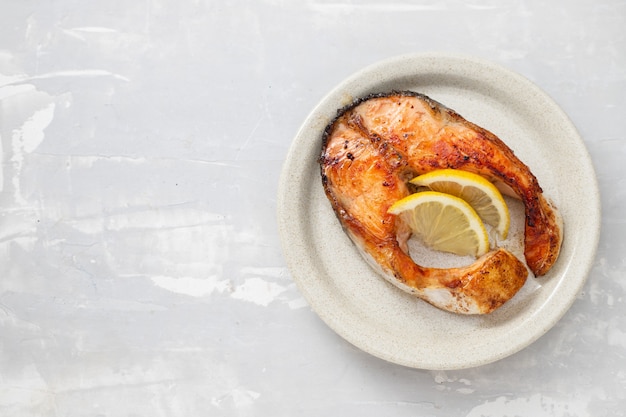 Fried salmon with lemon on the dish on ceramic background