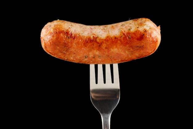 Fried sausage on a fork black background