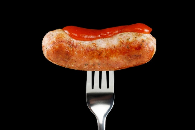 Fried sausage on a fork black background