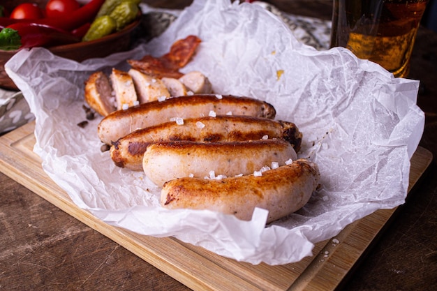 fried sausages lie on edible paper, next to red hot peppers and chopped cherry tomato