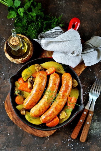 Fried sausages with potatoes, mushrooms and onions in a pan