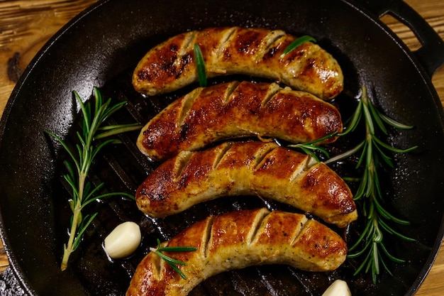 Fried sausages with rosemary garlic and spices in cast iron grill frying pan