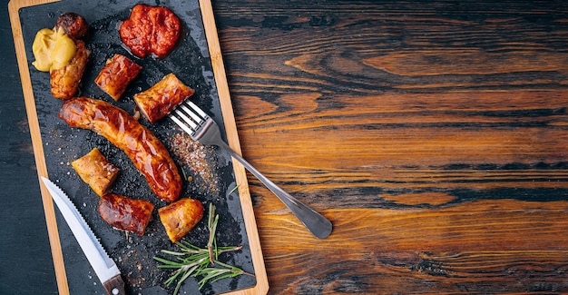 Fried sausages with sauces and spices on a stone plate