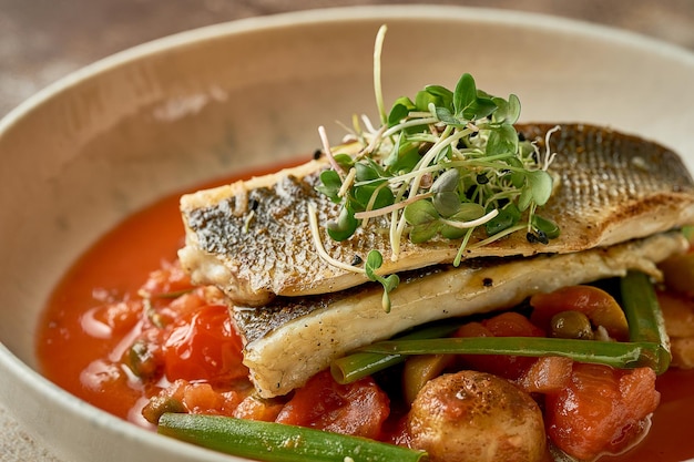 Fried sea bass fillet with potatoes in tomato sauce Selective focus closeup