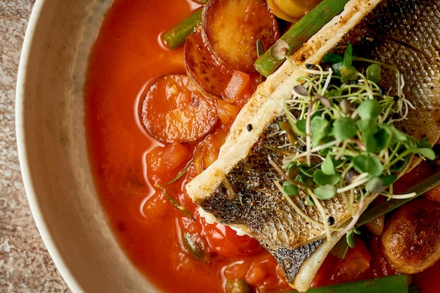 Fried sea bass fillet with potatoes in tomato sauce Selective focus closeup