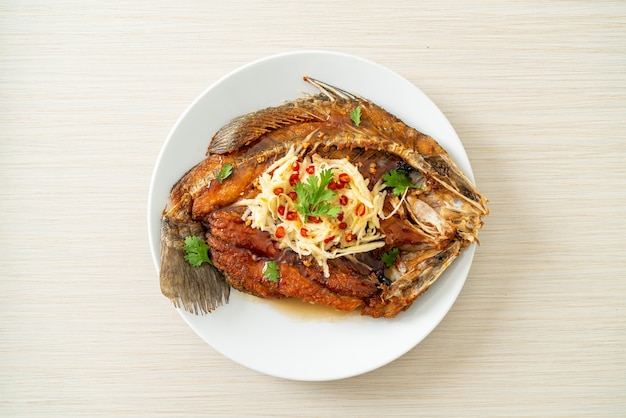 Fried Sea Bass Fish with Fish Sauce and Spicy Salad on plate