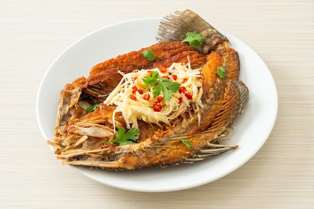 Fried Sea Bass Fish with Fish Sauce and Spicy Salad on plate