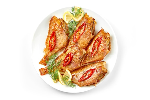 Fried sea bass in a white plate on a white background Closeup selective focus