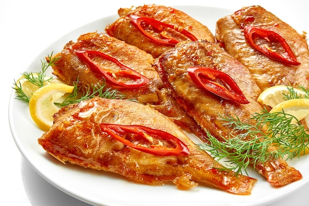 Fried sea bass in a white plate on a white background Closeup selective focus