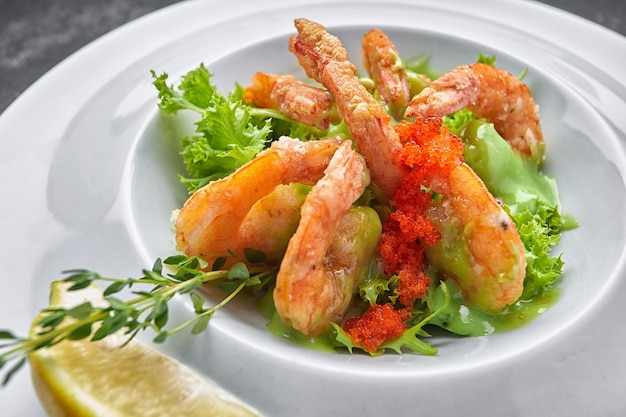 Fried shrimp with caviar herbs and sauce on a white plate