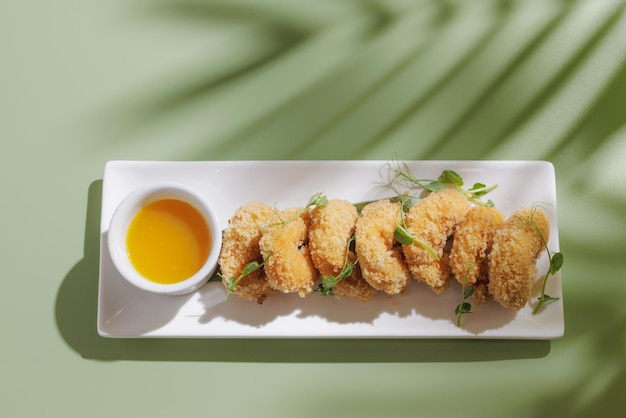 Fried shrimp with a cocktail on a light green background with a shadow from a palm tree top view