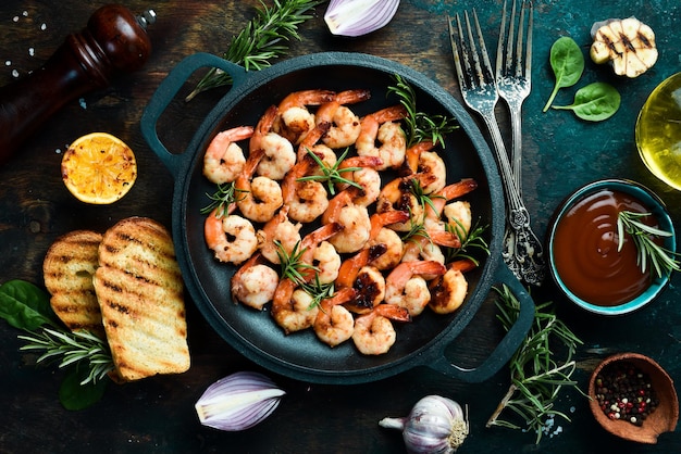 Fried shrimp with garlic and lemon in a pan Seafood On a black stone background