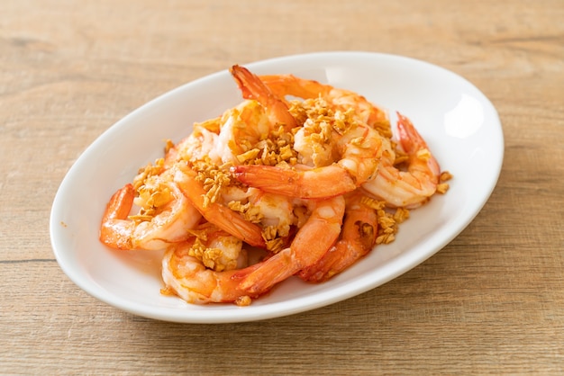 fried shrimps or prawns with garlic on white plate - seafood style