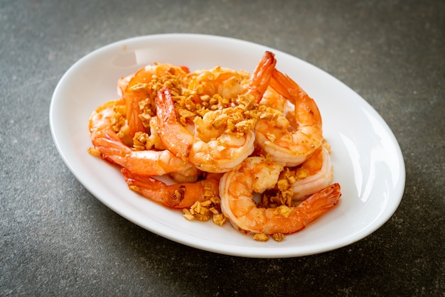 fried shrimps or prawns with garlic on white plate - seafood style