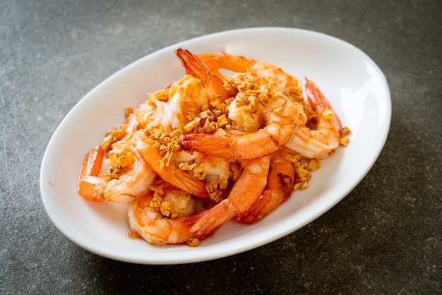 fried shrimps or prawns with garlic on white plate - seafood style