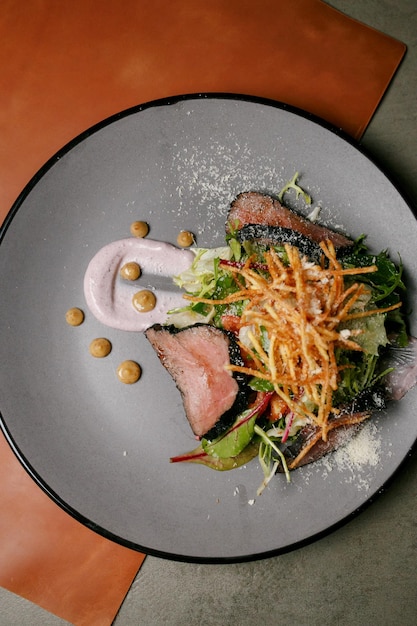 fried slices of veal, with herbs and french fries on a gray plate. fried slices of veal, with herbs.