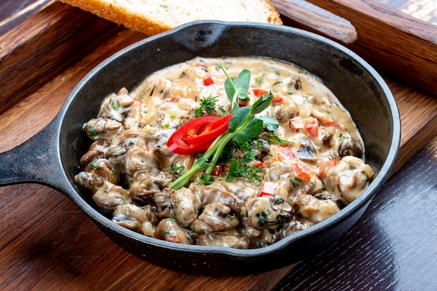 Fried snails in cream sauce in a cast iron pan On a wooden stand