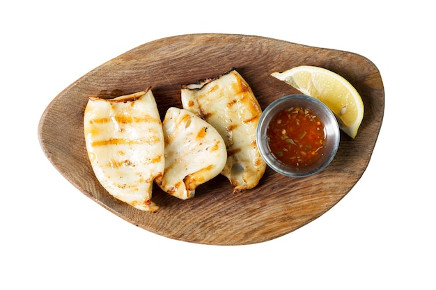 Fried squid carcasses with sauce and lemon served on a wooden board Appetizing popular snack Top view Closeup Isolated on white background