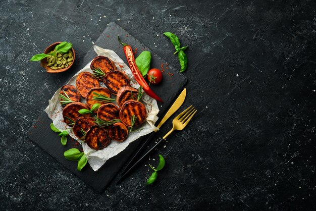 Fried sweet potatoes with rosemary paprika and chili peppers on a black stone plate Top view Free space for your text