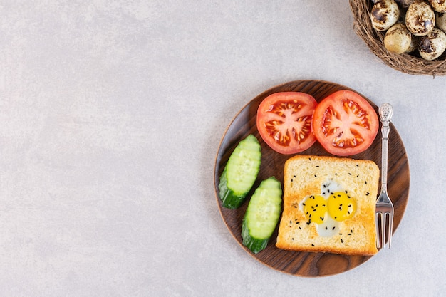 Fried toast with eggs and sliced vegetables placed in plate.