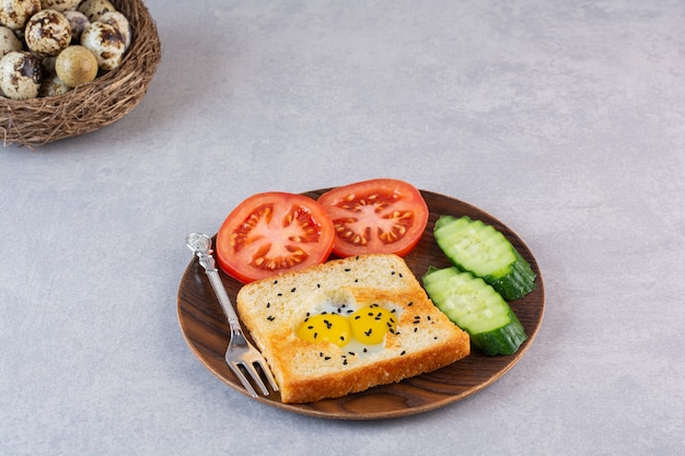 Fried toast with eggs and sliced vegetables placed in plate.