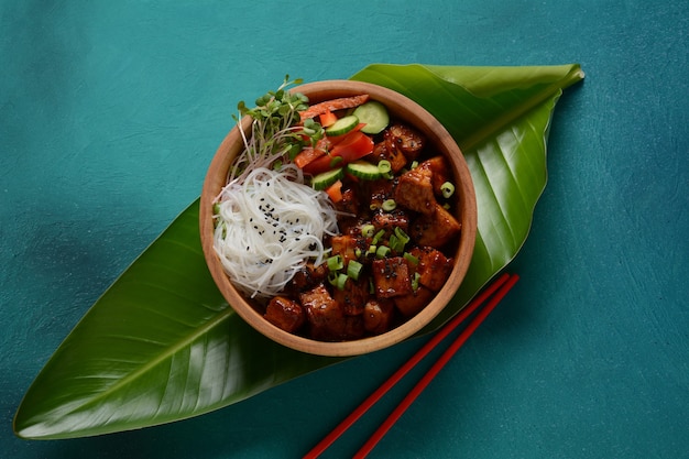 Fried tofu with rice crystal noodles in a wooden bowl.