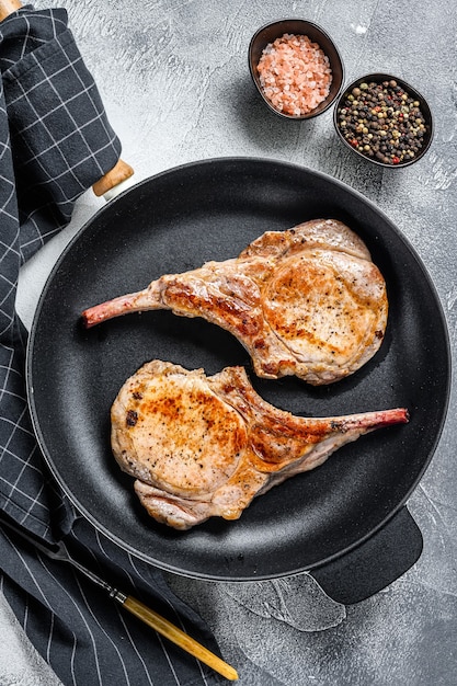 Fried tomahawk pork chop meat steak in a pan. White background. Top view.