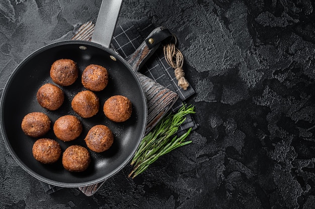 Fried Vegan plant based Meatballs in a skillet with herbs Black background Top view Copy space