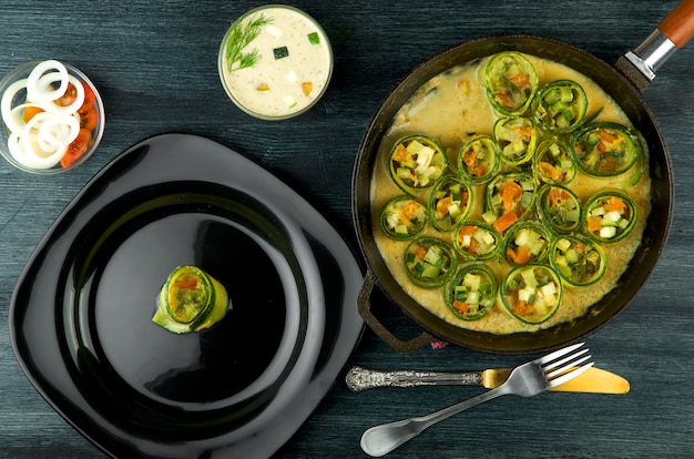 Fried young sliced courgettes in a pan on a dark surface