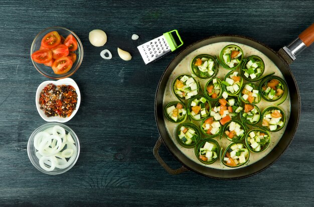 Fried young sliced courgettes in a pan on a dark surface