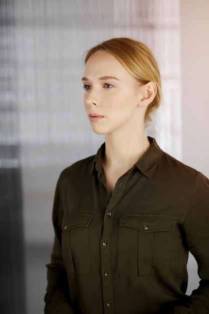 Friendly adult casual dressed business woman standing straight in sunny office. Business headshot.