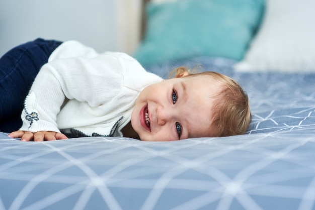 Friendly baby girl smile lying on the bed