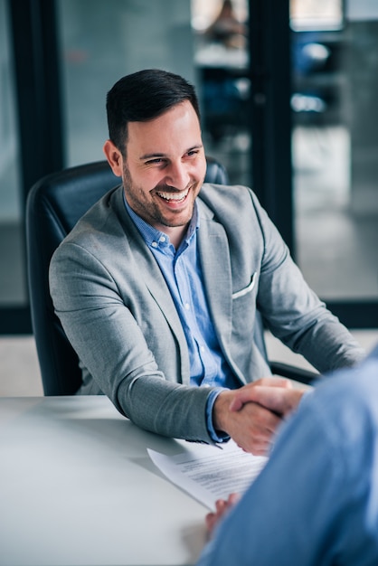 Friendly business handshake. Smiling handsome elegant man handshaking with employee.