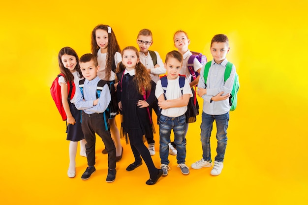 The friendly classmates are hugging on a yellow background