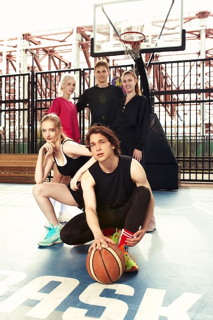 A friendly company of guys and girls are having fun on the basketball court they are going to play basketball