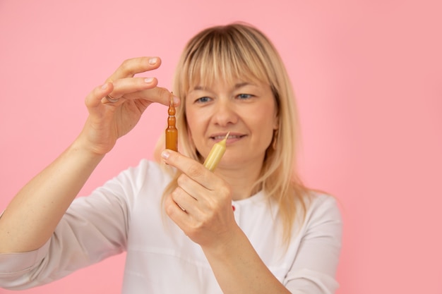 Friendly cosmetologist doctor in white medical uniform examines face and body care products. Aromatherapy. Fruit acids.Hyaluronic acid. Beauty salons. Modern cosmetology. Lifestyle.