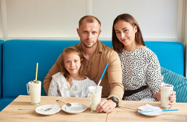 Friendly family having milkshakes in the cafe