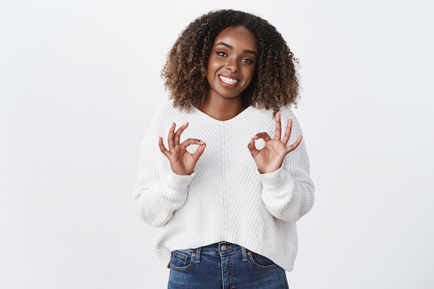 Friendly-looking cheerful cute african-american plump woman smiling delighted show okay ok approval gesture like recommend service good job, say no problem assure she okay, white wall